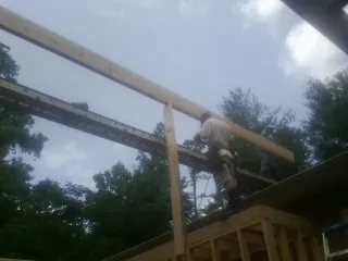 Carpenter setting a ridge beam over a new addition frame — Ice Dam Removal by Roofing Brothers in Mears