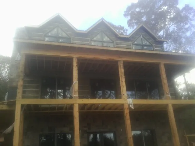 Dormers and porch framing on a large log home under construction — Roof Coating work by our crew in Mears