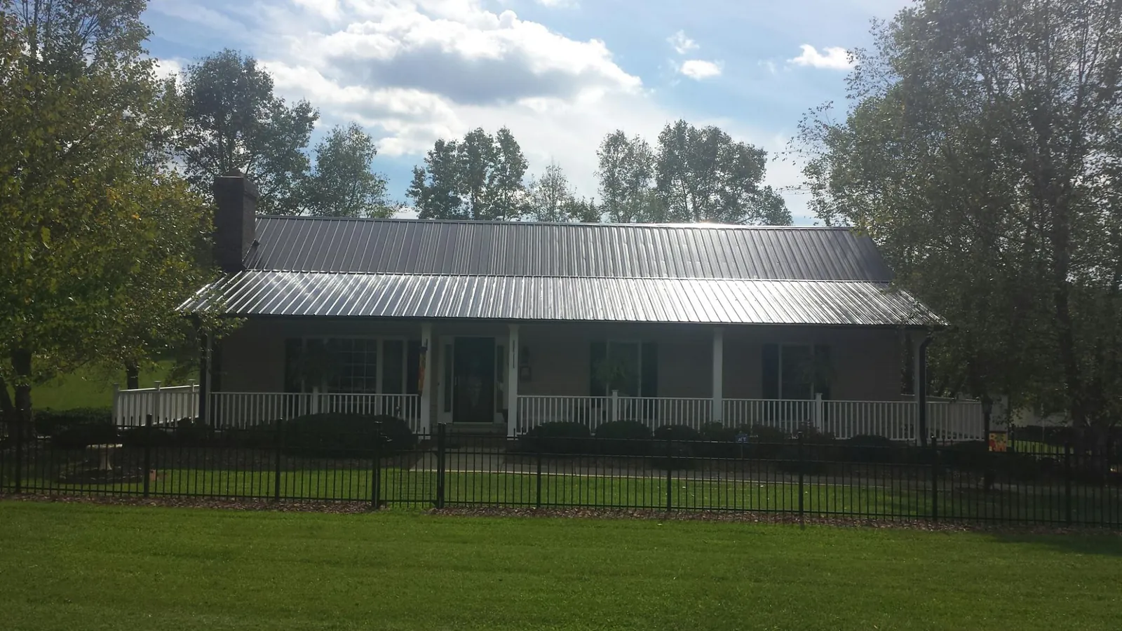 Gray metal roof on a brick ranch with a full width front porch — Gutter Guard Installation work by our crew in Mears