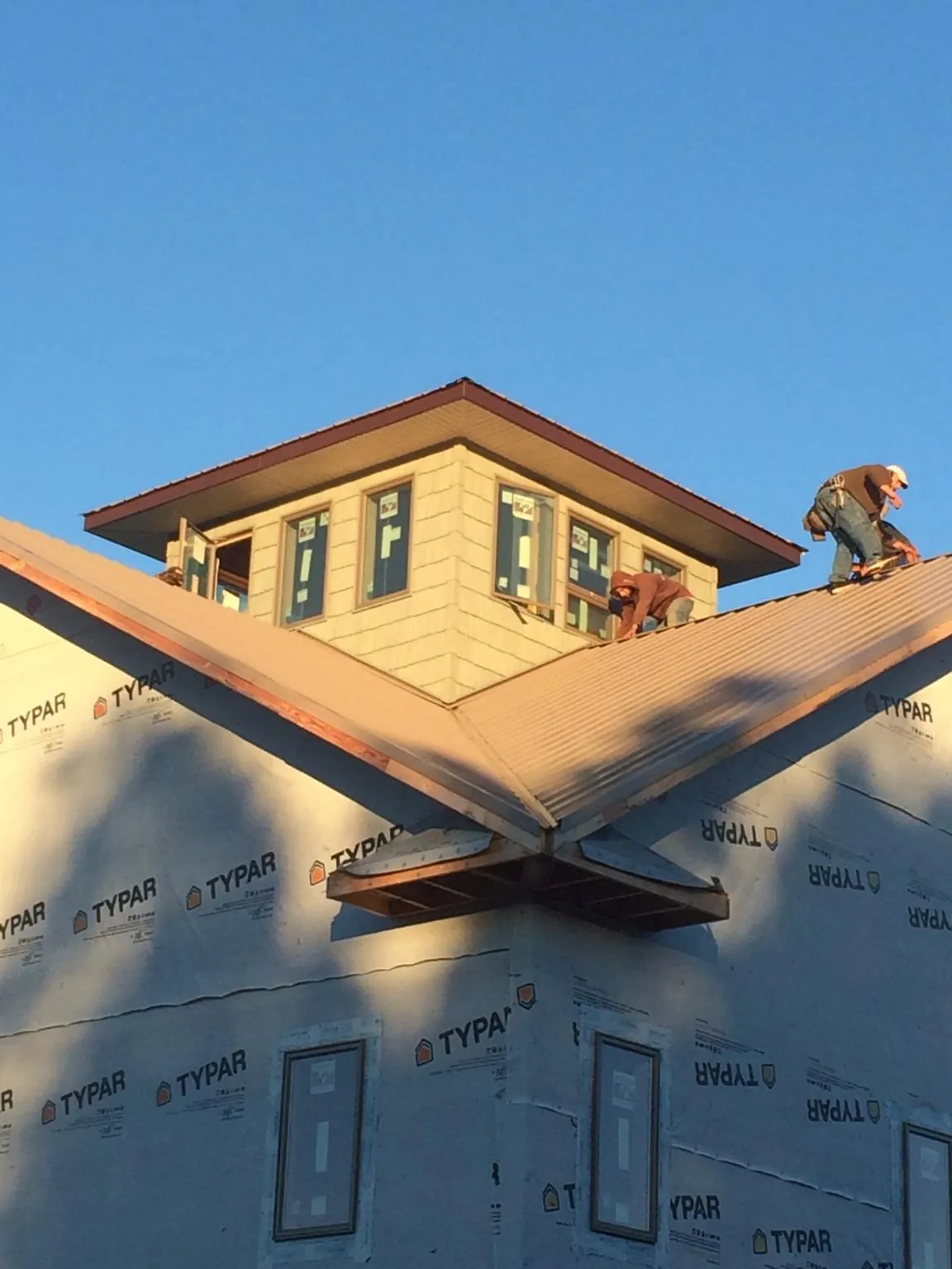 Roofers working around a rooftop cupola on a new metal roof at sunset — Roof Waterproofing in Mears by Roofing Brothers